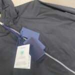 Giacca Prada navy moderna con cappuccio, etichette nuove e dettaglio resistente e stiloso.