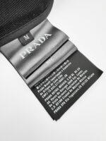 Etichetta Prada nero con logo argento, taglia M e istruzioni di cura minimaliste.