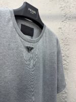 T-shirt grigia Prada con logo triangolare, stile casual ed elegante, morbida e versatile.