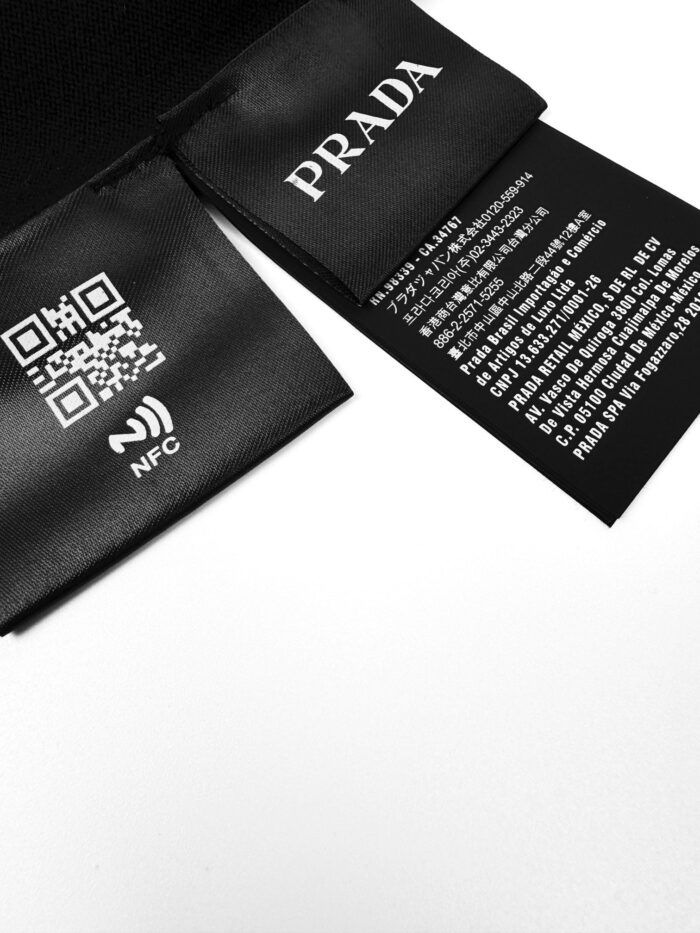 Etichette Prada in raso nero con QR code, NFC e istruzioni di cura di lusso.