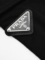 Logo Prada in metallo su tessuto nero, simbolo di lusso e stile italiano esclusivo.