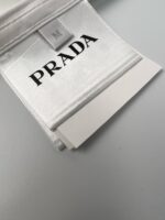 Etichetta Prada di lusso con logo elegante su sfondo bianco satinato.
