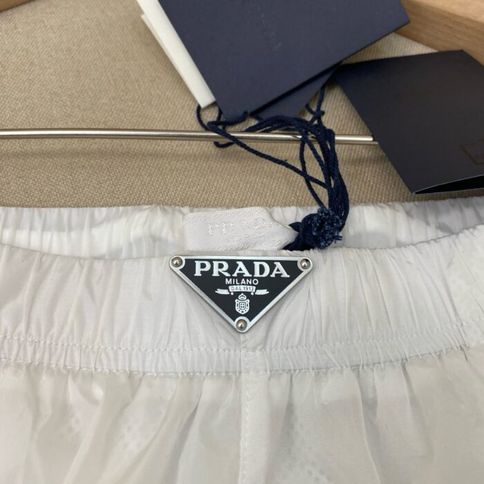 Shorts bianchi Prada con logo iconico, tessuto leggero e design minimalista.