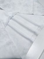 Tessuto bianco leggero, lisciato e raffinato con pieghe e dettagli di alta qualità.