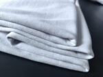 Pieghe di tessuto bianco morbido, elegante su sfondo scuro, ideale per moda e interior design.