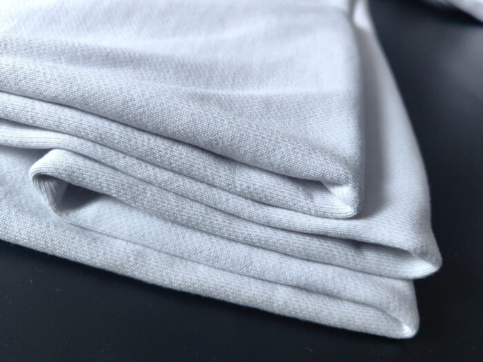 Pieghe di tessuto bianco morbido, elegante su sfondo scuro, ideale per moda e interior design.