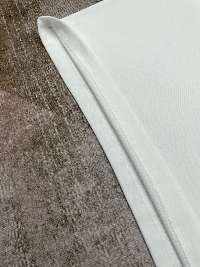 Tessuto bianco pulito e contrasto con sfondo texturizzato caldo, eleganza minimalista e tranquillità.