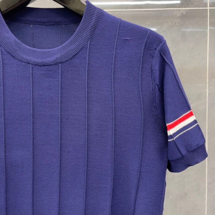 Camicia viola con dettagli sportivi a strisce rosso, bianco e blu sulla manica.