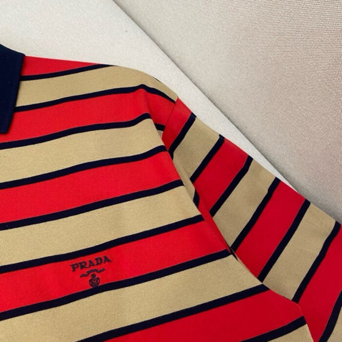 Polo Prada a righe rosso e beige con colletto navy, stile elegante e casual.