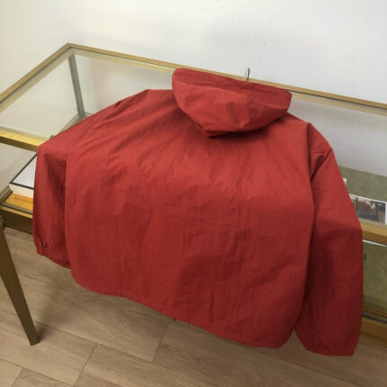 Giacca rossa elegante in esposizione su tavolo di legno e vetrina di boutique raffinata.