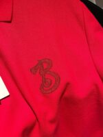 Maglietta polo rossa con ricamo elegante della lettera B, tessuto morbido e stile versatile.