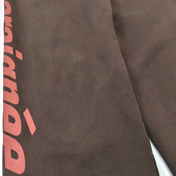 Pantaloni marroni con logo rosa verticale, stile casual e moderno, tessuto morbido e confortevole.