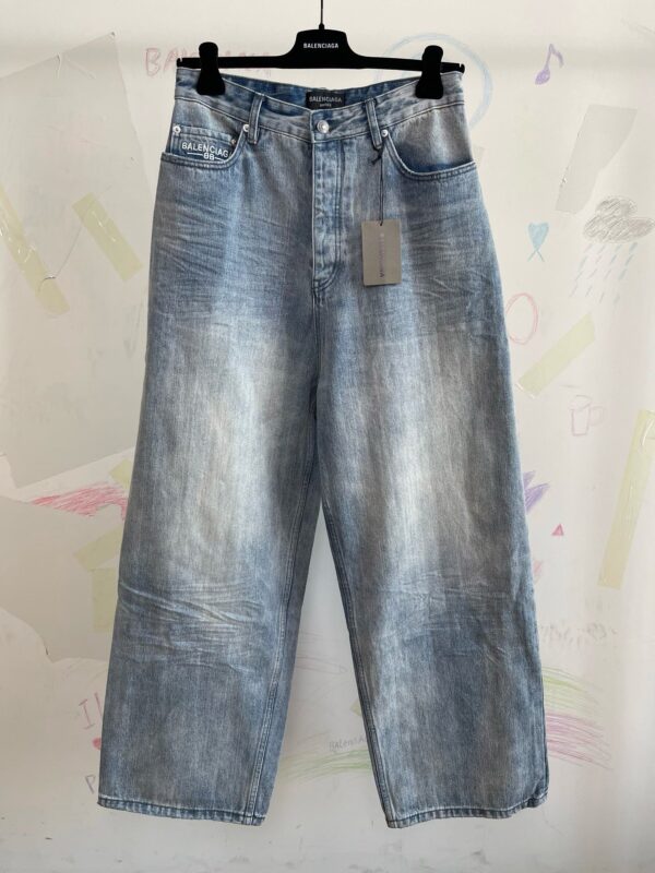 Jeans donna in denim chiaro, stile vintage, vestibilità ampia e vita alta, su appendiabiti.