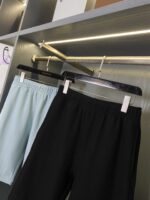 Pantaloncini casual blu e neri su espositore moderno, perfetti per estate e stile versatile.