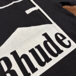 T-shirt nero con grafica montagna e logo Rhude, stile streetwear minimalista e di tendenza.