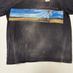 Maglietta vintage nera con paesaggio colorato e silhouette sulla croce, scritta SAINT MXB in rosso.