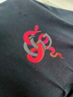 Design astratto con serpente rosa su tessuto scuro, stile artistico e simbolico.