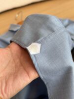 Polsino blu con logo esagonale, dettaglio di qualità e stile moderno.
