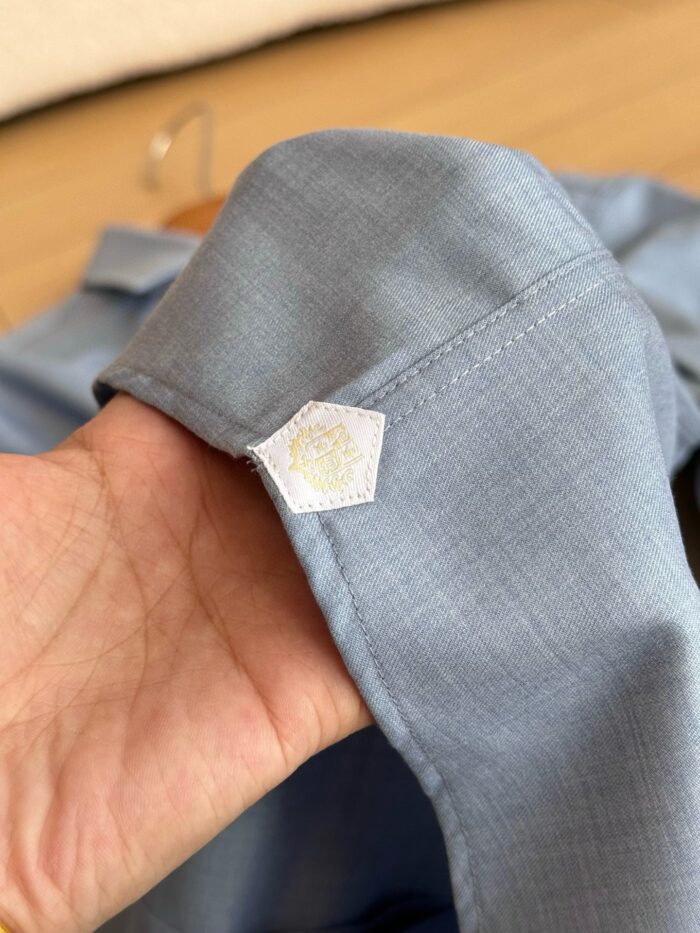 Polsino blu con logo esagonale, dettaglio di qualità e stile moderno.
