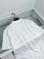 Maglietta bianca semplice appesa in armadio minimalista, perfetta per un look casual e pratico.