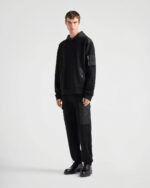 Abbigliamento streetwear nero monocromatico con hoodie, pantaloni oversize e scarpe eleganti in stile urbano.