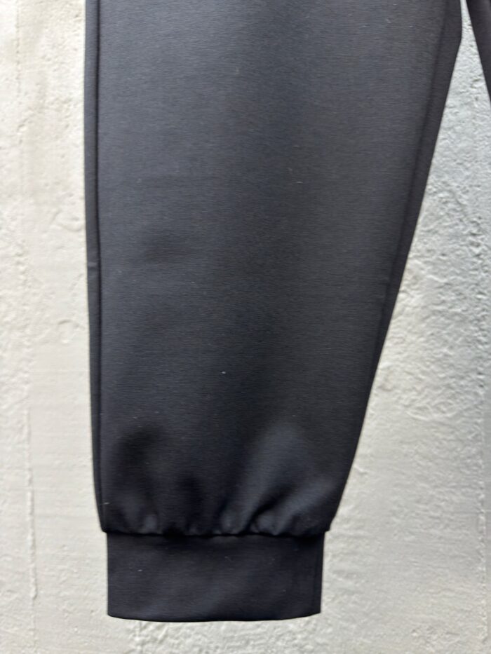 Pantaloni jogger neri con polsino elasticizzato, tessuto lucido e design moderno.