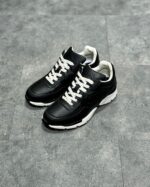 Scarpe sportive nere con lacci bianchi, suola bianca resistente, stile moderno e comfort.