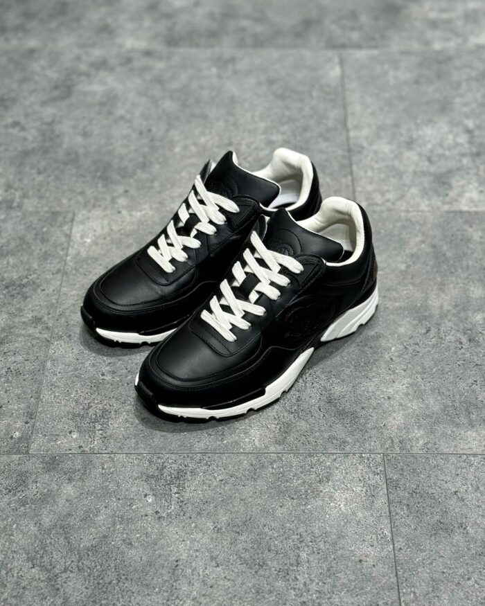 Scarpe sportive nere con lacci bianchi, suola bianca resistente, stile moderno e comfort.