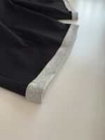 Dettaglio dellorlo di una maglietta nera con fascia grigia, stile minimalista e comodo.