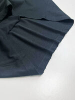 Tessuto nero elasticizzato, delicato e lucido, perfetto per abbigliamento moderno e versatile.