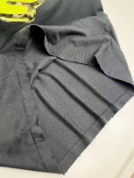 Maglietta nera con pieghe, logo giallo e dettagli eleganti, stile moderno e versatile.