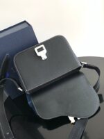 Borsa nera minimalista in pelle con chiusura metallica, elegante e moderna, su superficie riflettente.