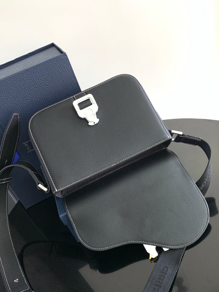 Borsa nera minimalista in pelle con chiusura metallica, elegante e moderna, su superficie riflettente.