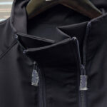 Giacca nera moderna con collo alto, doppie cerniere e design minimalista versatile e elegante.