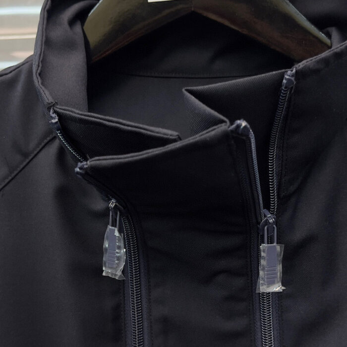 Giacca nera moderna con collo alto, doppie cerniere e design minimalista versatile e elegante.