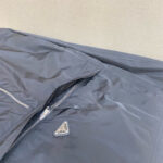 Giacca nera elegante con zip, logo minimalista, tessuto lucido e design moderno.
