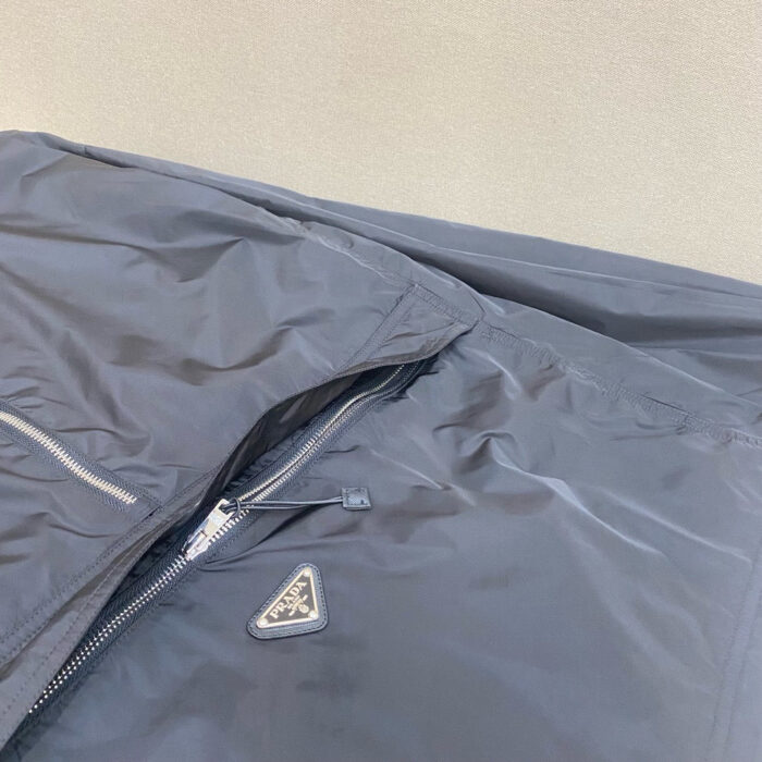 Giacca nera elegante con zip, logo minimalista, tessuto lucido e design moderno.