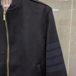Giacca bomber nera con strisce sportive, zip dorata e interno a righe rosse e bianche.