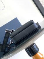 Borsa nera di pelle moderna su tavolo di vetro con dettagli eleganti e hardware lucido.