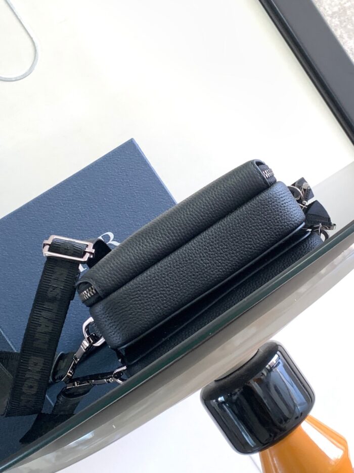 Borsa nera di pelle moderna su tavolo di vetro con dettagli eleganti e hardware lucido.