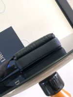 Borsa Dior in pelle nera su tavolo moderno, elegante e raffinato, con libro abbinato.