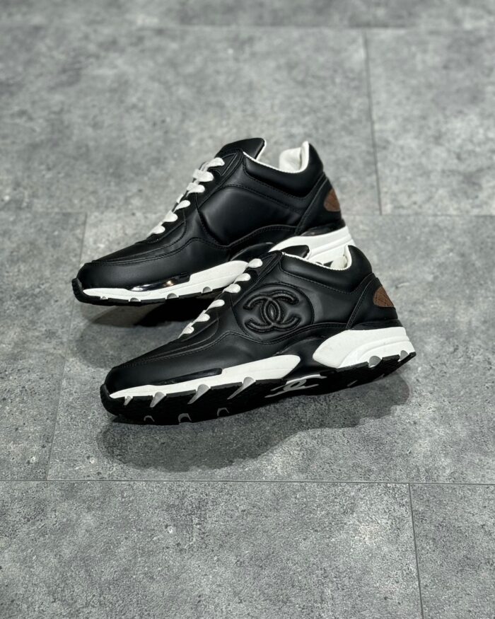 Sneakers nere di lusso in pelle con dettagli bianchi, logo impresso, stile elegante e sportivo.