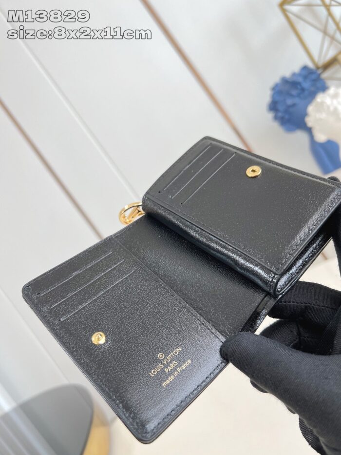 Portafoglio nero in pelle elegante con dettagli dorati, compatto e stile minimalista.