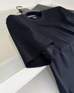 Maglietta nera casual e versatile con scollo rotondo e tessuto lucido, moderna e semplice.