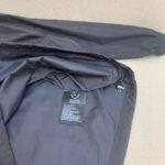 Giacca nera in nylon con dettagli elastici, stile minimalista e stile adatto a ogni occasione.