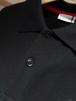 Maglietta polo nera elegante con colletto strutturato, bottoni rifiniti e dettaglio rosso di stile.