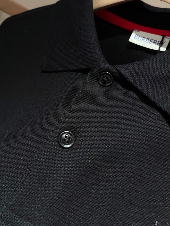 Maglietta polo nera elegante con colletto strutturato, bottoni rifiniti e dettaglio rosso di stile.