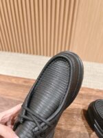 Scarpa nera moderna in pelle con dettagli rigati, punta rotonda e doppio lacci elegante.