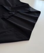 Abito nero satiné con plissé elegante, design fluido e raffinato per occasioni speciali.