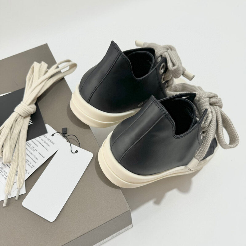 Scarpe nere moderne con suola crema, dettagli minimalisti, su packaging elegante e pratico.
